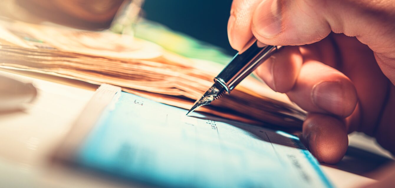 writing-a-check-with-a-fountain-pen-and-stacks-of-2025-05-31-22-39-14-utc-min
